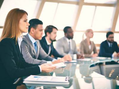 29717217 - row of business people listening to presentation at seminar with serious woman on foreground